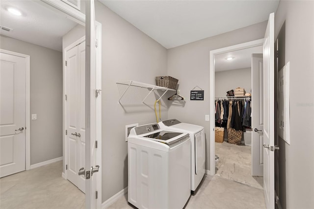 clothes washing area with washing machine and clothes dryer, baseboards, and laundry area
