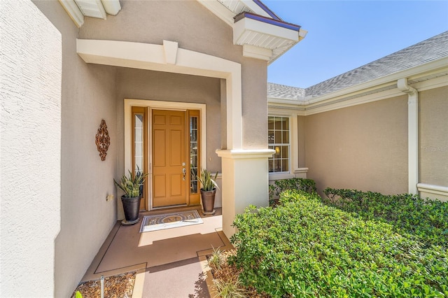 property entrance with a shingled roof and stucco siding