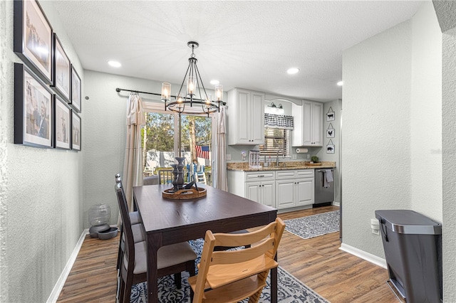 dining room featuring light wood-style floors, baseboards, and a textured wall