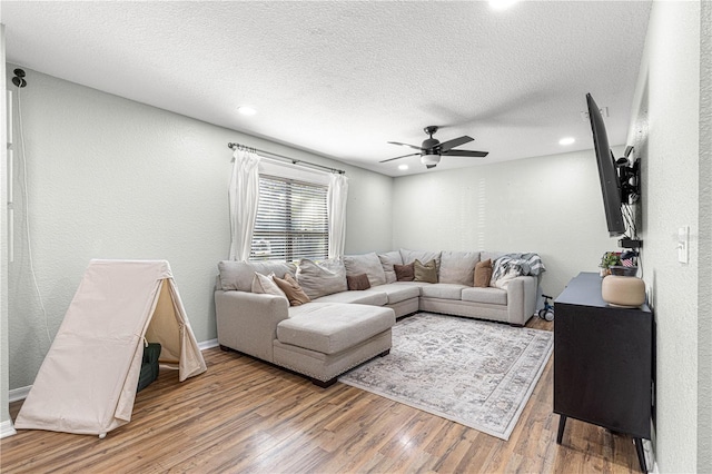 living area featuring recessed lighting, a textured wall, ceiling fan, a textured ceiling, and wood finished floors