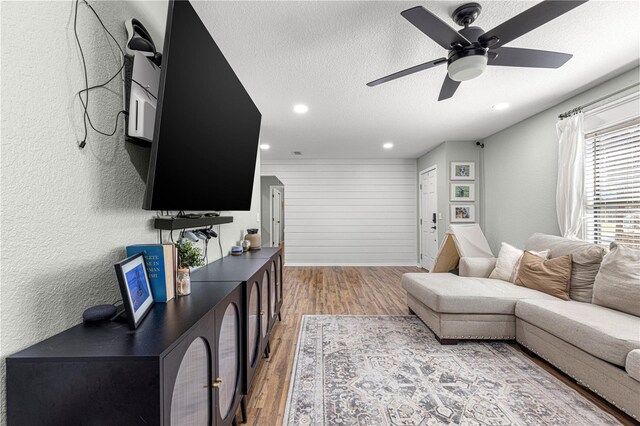 living room featuring a textured wall, light wood-style flooring, ceiling fan, a textured ceiling, and recessed lighting