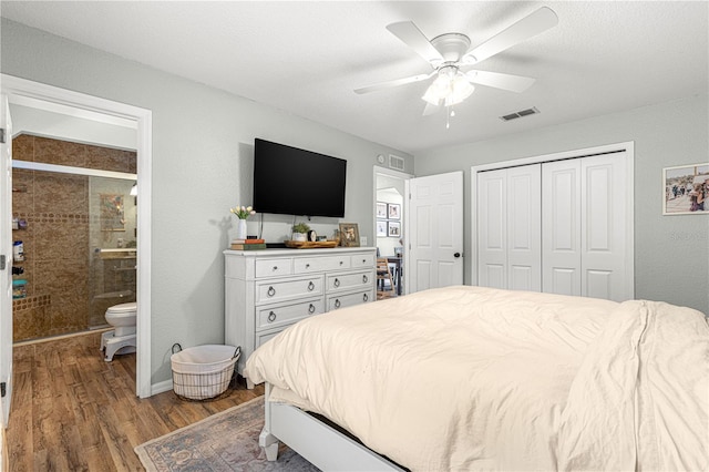 bedroom with ceiling fan, connected bathroom, wood finished floors, visible vents, and a closet