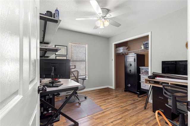 home office featuring a ceiling fan, a textured ceiling, baseboards, and wood finished floors