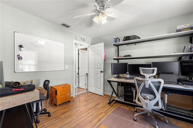 office area with ceiling fan, a textured ceiling, wood finished floors, and visible vents