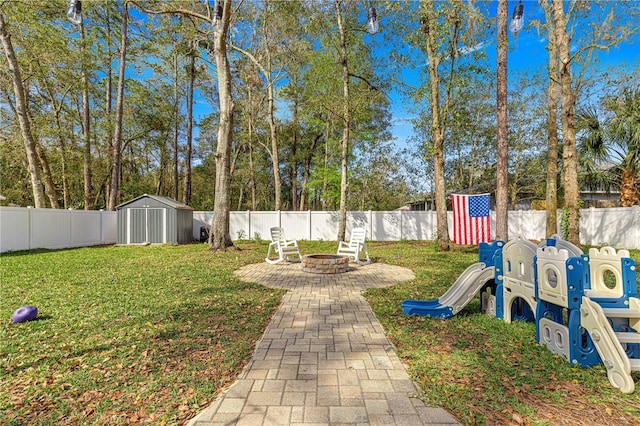 view of yard with a fire pit, a shed, an outdoor structure, and a fenced backyard