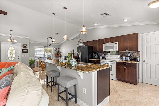 kitchen with visible vents, a breakfast bar, a sink, open floor plan, and white appliances