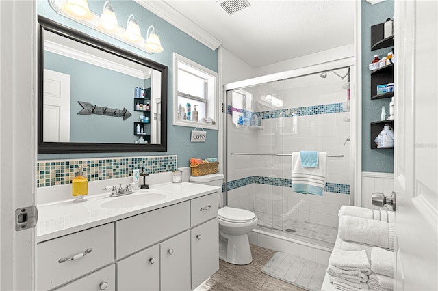 full bathroom featuring vanity, visible vents, a stall shower, crown molding, and toilet