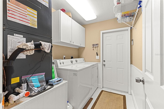 laundry room with light tile patterned flooring, cabinet space, a textured ceiling, and washer and clothes dryer