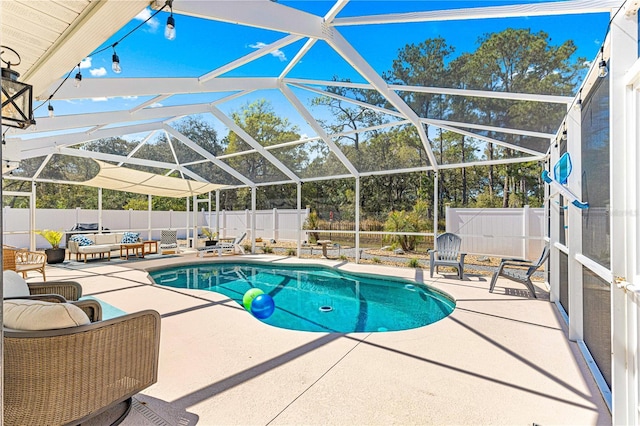 view of swimming pool featuring glass enclosure, a patio area, and a fenced backyard