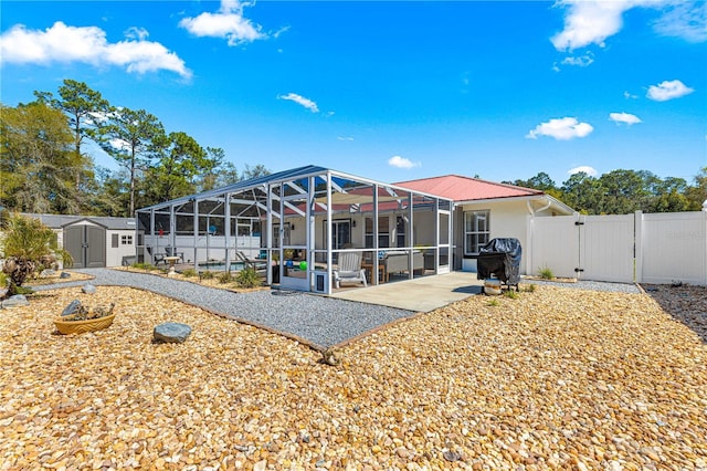 back of property with a storage shed, a fenced backyard, an outdoor structure, a patio area, and a gate