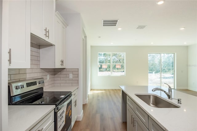 kitchen featuring stainless steel appliances, visible vents, backsplash, white cabinetry, and a sink