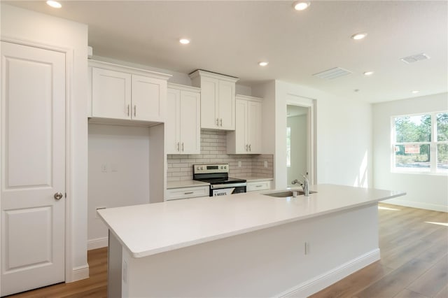 kitchen featuring a center island with sink, white cabinets, electric stove, backsplash, and a sink