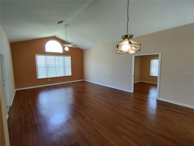 empty room featuring lofted ceiling, visible vents, a ceiling fan, baseboards, and dark wood-style floors