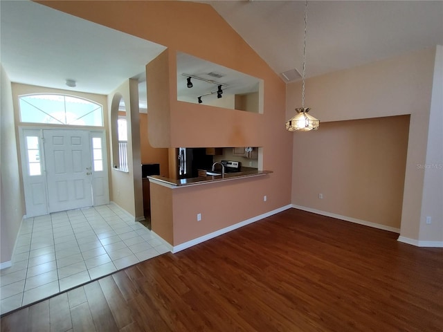 entryway with rail lighting, vaulted ceiling, baseboards, and wood finished floors