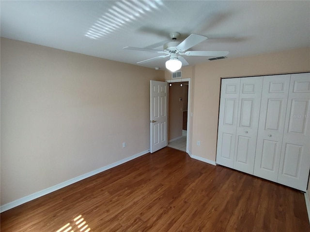 unfurnished bedroom featuring baseboards, a closet, visible vents, and wood finished floors