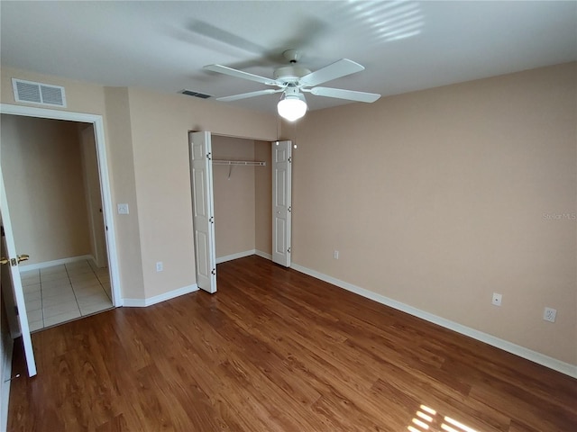 unfurnished bedroom featuring baseboards, a closet, visible vents, and wood finished floors