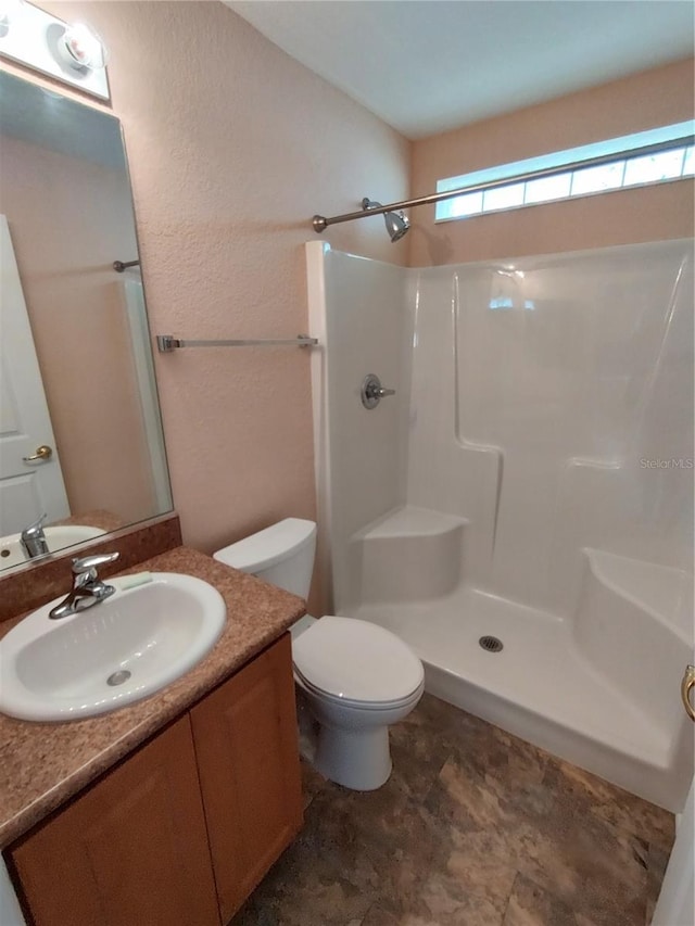 full bath featuring toilet, a shower, and vanity