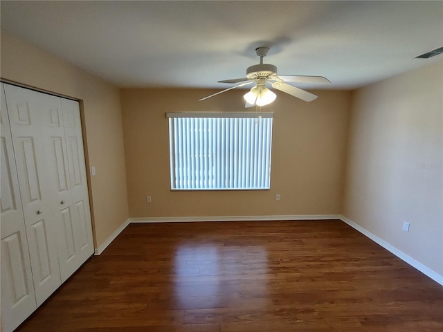 unfurnished bedroom featuring ceiling fan, wood finished floors, visible vents, baseboards, and a closet