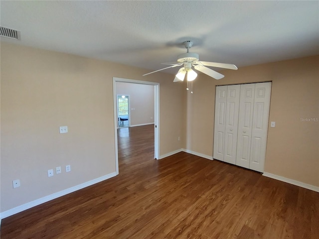 unfurnished bedroom featuring a closet, visible vents, baseboards, and wood finished floors