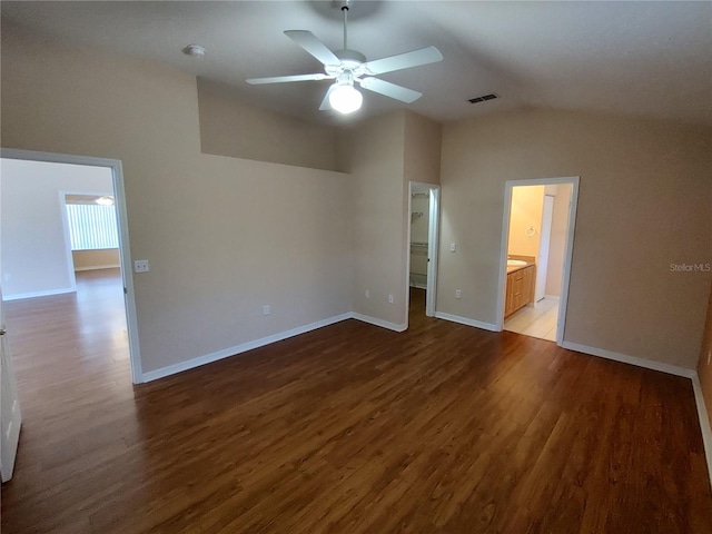 interior space featuring wood finished floors, visible vents, baseboards, vaulted ceiling, and a walk in closet