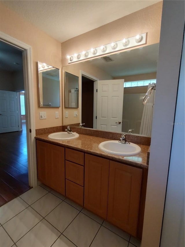 full bathroom with tile patterned floors, a sink, a textured ceiling, and double vanity