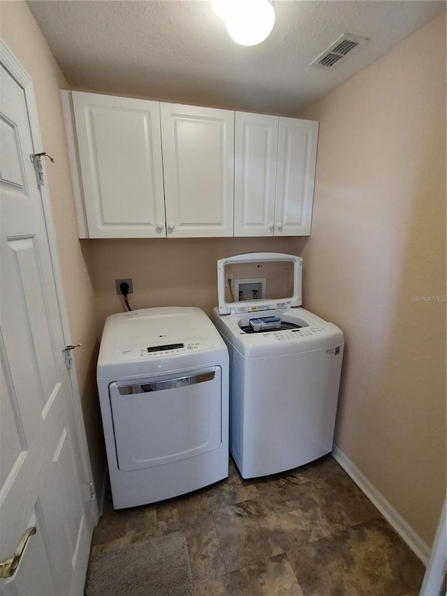 laundry area featuring cabinet space, baseboards, visible vents, washer and clothes dryer, and a textured ceiling