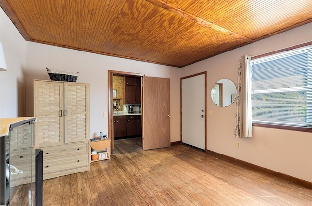 interior space featuring light wood finished floors, wooden ceiling, and baseboards