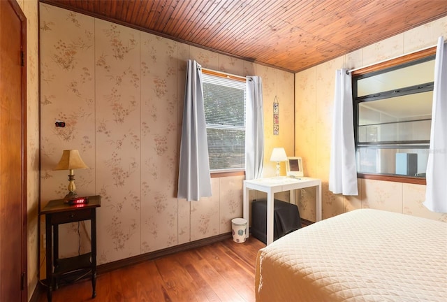 bedroom featuring baseboards, wood-type flooring, wooden ceiling, and wallpapered walls