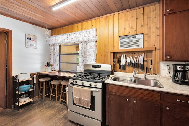 kitchen featuring a wall mounted air conditioner, dark wood-style flooring, a sink, light countertops, and gas stove