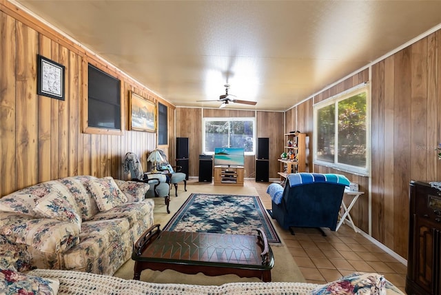 living area with a ceiling fan, light tile patterned flooring, and wood walls