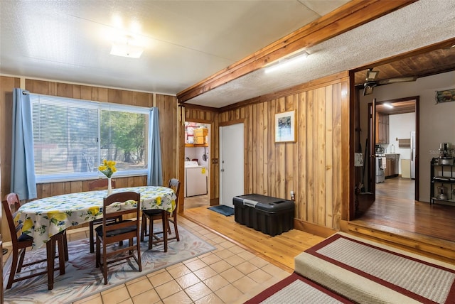 dining space with wooden walls, washer / clothes dryer, and beamed ceiling