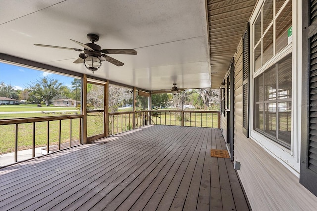 wooden deck featuring a lawn and ceiling fan