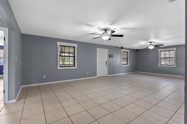 empty room featuring light tile patterned floors, a ceiling fan, baseboards, and a textured ceiling