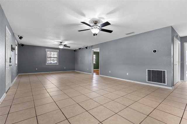 empty room featuring light tile patterned flooring, visible vents, a textured ceiling, and a ceiling fan