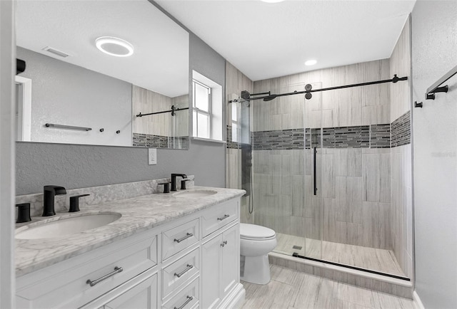 bathroom featuring visible vents, a shower stall, toilet, and a sink