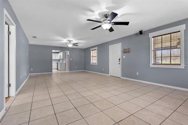 unfurnished living room with light tile patterned floors, visible vents, baseboards, and a ceiling fan