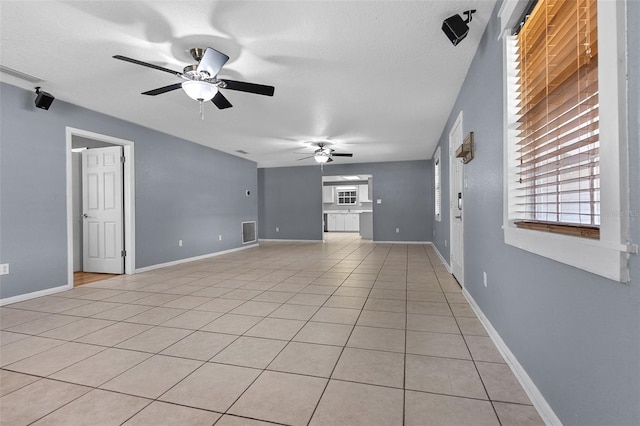 unfurnished living room featuring visible vents, baseboards, light tile patterned flooring, a textured ceiling, and a ceiling fan