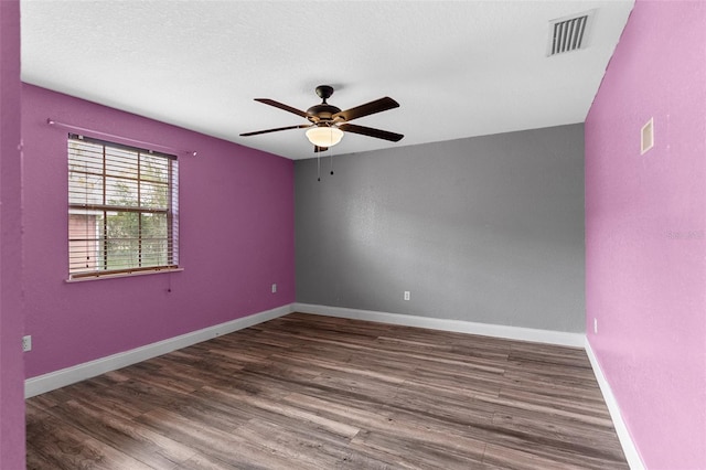 empty room with visible vents, ceiling fan, baseboards, wood finished floors, and a textured ceiling