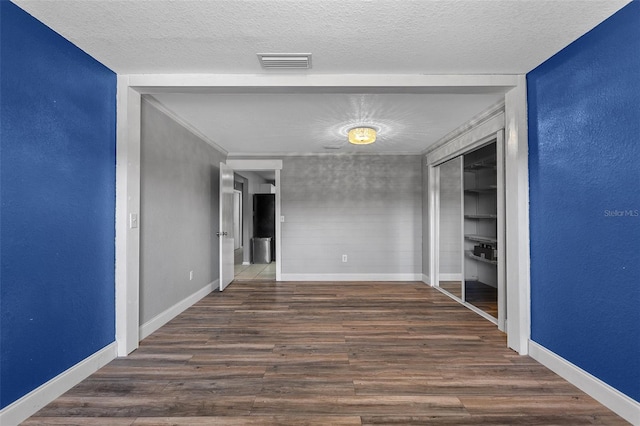 interior space with visible vents, a textured ceiling, baseboards, and wood finished floors