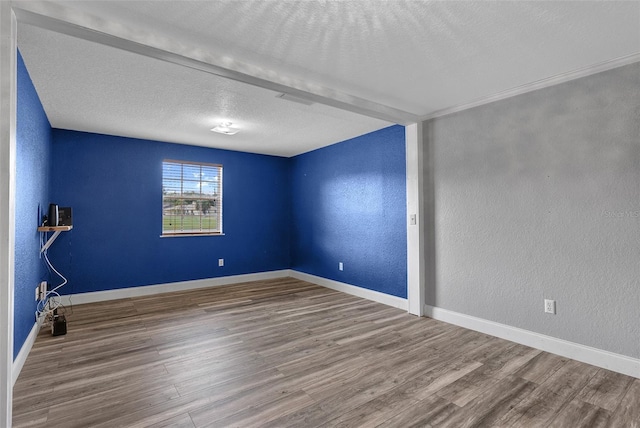 unfurnished room featuring a textured ceiling, wood finished floors, and a textured wall