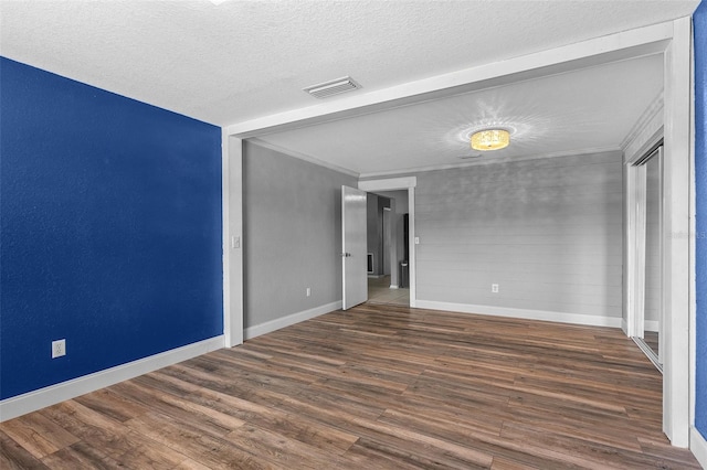 empty room with visible vents, crown molding, baseboards, wood finished floors, and a textured ceiling