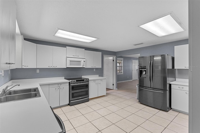 kitchen featuring visible vents, light countertops, light tile patterned floors, stainless steel appliances, and a sink