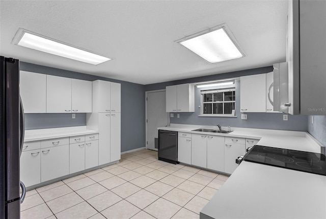 kitchen featuring light countertops, freestanding refrigerator, black dishwasher, and a sink