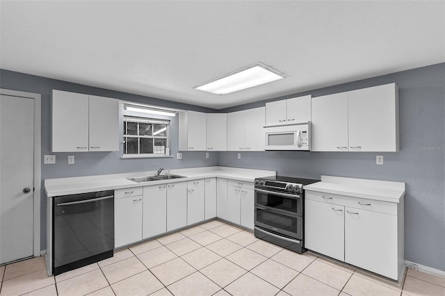 kitchen with a sink, double oven range, light countertops, white microwave, and dishwasher