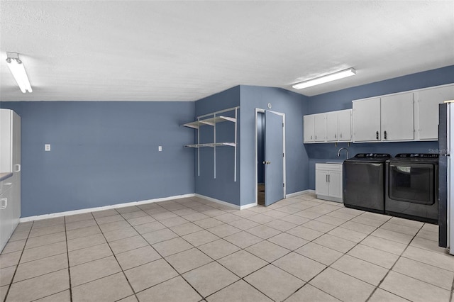 kitchen with a sink, a textured ceiling, white cabinetry, baseboards, and washing machine and clothes dryer