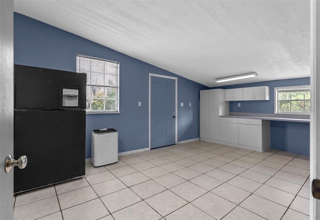 kitchen featuring lofted ceiling, freestanding refrigerator, light countertops, white cabinets, and a textured ceiling