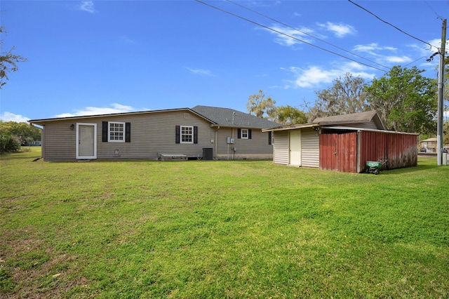 rear view of property featuring central air condition unit, an outbuilding, a lawn, and a shed