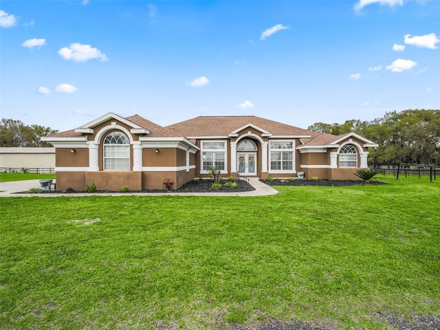 view of front of property with a front yard, french doors, fence, and stucco siding