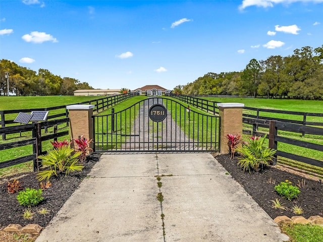 view of gate with a rural view, a yard, and fence