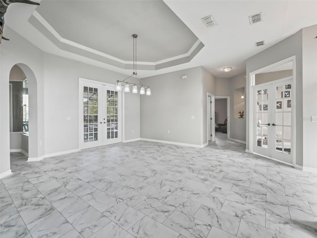 spare room featuring french doors, a raised ceiling, visible vents, and baseboards